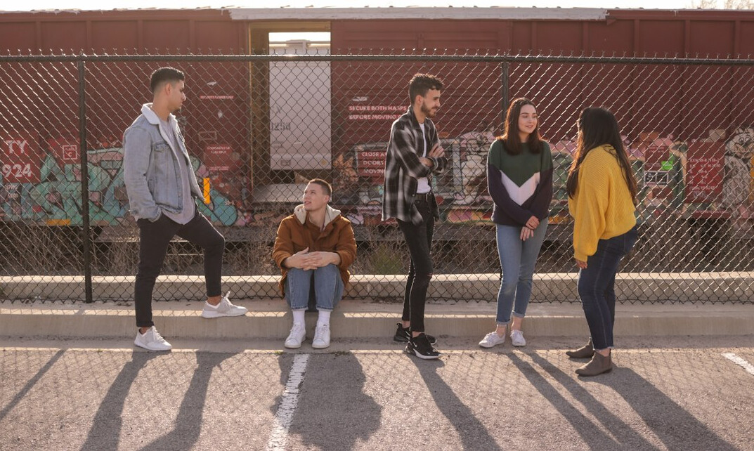 Group of young students talking around a laptop